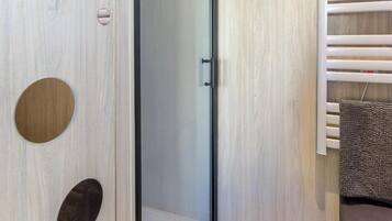 Un baño moderno con pared de madera, cabina de ducha de vidrio y un perchero para toallas.