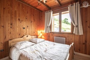 Cozy bedroom with a single bed, floral-patterned duvet, and wooden walls.