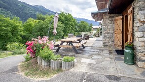 A stone building with a wooden door and a patio area with a table and chairs.