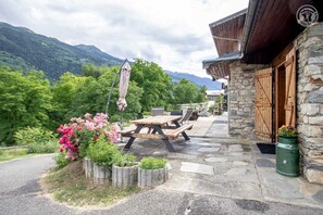 Relax in a serene outdoor seating area surrounded by lush greenery and majestic mountains.
