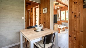 A wooden interior with a dining table, chairs, and a kitchen area.
