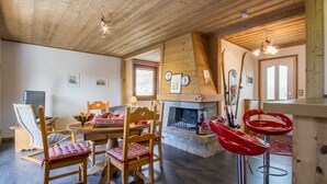 Interior acogedor de una cabaña de madera con comedor, chimenea y equipo de esquí.