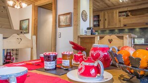 Interior de madera con comedor que presenta vajilla roja y blanca, un reloj y un cabecero de madera con un corte en forma de corazón.