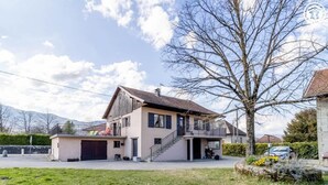 Ein zweistöckiges Haus mit Balkon, Garage und Treppe zum Obergeschoss.