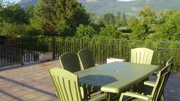 Eine Terrasse mit Tisch und Stühlen mit Blick auf eine gebirgige Landschaft.