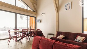 Una habitación amplia con una gran mesa de comedor y sillas, un sofá rojo y un televisor fijado a la pared.