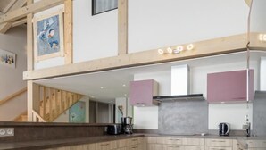 Una cocina moderna con armarios de madera, encimera oscura y suelo de baldosas.