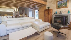 Ein modernes Wohnzimmer mit einer Eckcouch, einem schwarzen Ledersessel und einem Kamin.