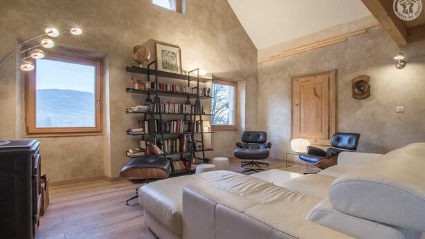 Ein gemütliches Schlafzimmer im Loft-Stil mit großem Fenster, einer integrierten Bücherreol und einer bequemen Couch sowie einem Fernseher.