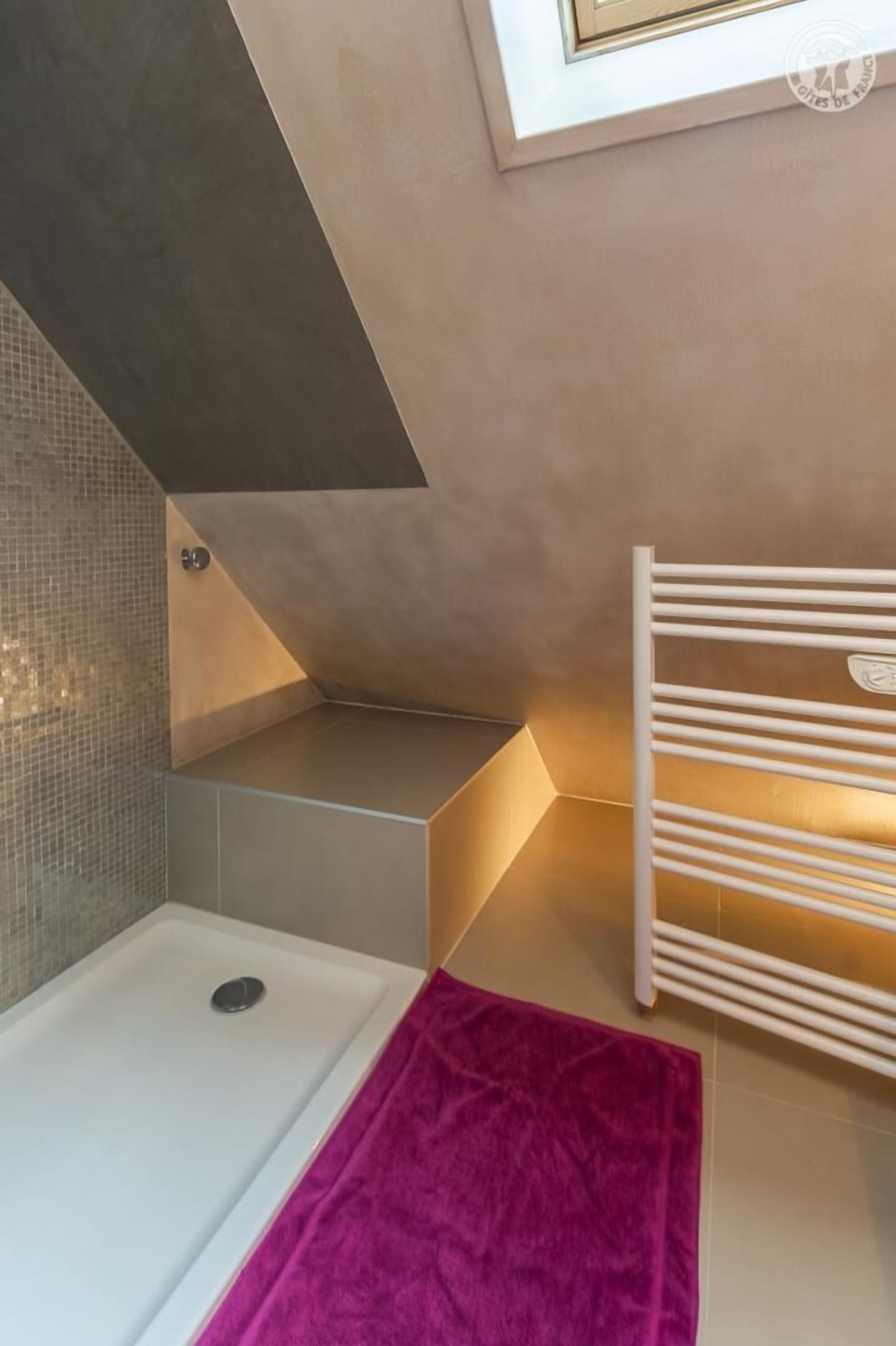 A modern bathroom with a bathtub, a shower, and a towel rack.