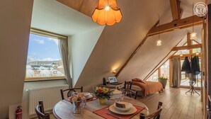 A cozy, well-lit dining area with a wooden table, chairs, and a view of the snowy landscape outside. - UN Loft A LA Campagne (SAINT JEAN D'ARVEY)