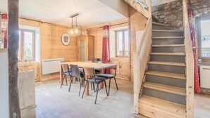 A wooden interior with a dining area, a staircase, and a view through a window. - LES Luzes - Lescheraines (LESCHERAINES)