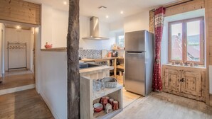 A modern kitchen with a central island, stainless steel appliances, and a view of the countryside through a window. - LES Luzes - Lescheraines (LESCHERAINES)