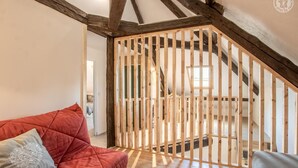 A room with a red sofa, a wooden partition, and a staircase with exposed beams. - LES Luzes - Lescheraines (LESCHERAINES)