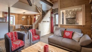 A cozy wooden interior with a staircase, a dining area, and a sofa with decorative pillows. - LES Luzes - Lescheraines (LESCHERAINES)