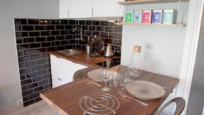 Eine kleine Küche mit schwarzem Fliesenrückwand, einer Holz Arbeitsplatte und einem Regal mit Teedosen.