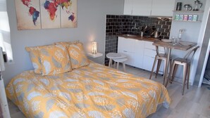 Ein gemütliches Schlafzimmer mit Bett, einer kleinen Küchenzeile und einer Weltkarte an der Wand.