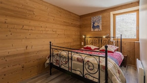 A wooden-paneled room with a bed, a window, and a ceiling light. - Gites DE Beaune - LE Brequin (SAINT MICHEL DE MAURIENNE)