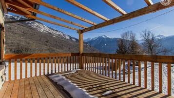 Une terrasse en bois offrant une vue sur des montagnes enneigées.