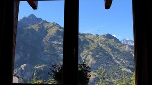 A mountain view from a window with a wooden frame, featuring a mountain range and some greenery in the foreground. - LE PIN Cembro LA Norma (LA NORMA VILLARODIN BOURGET)