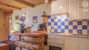 A rustic kitchen with wooden log seating, a gas stove, and checkered blue and white tiles. - LE PIN Cembro LA Norma (LA NORMA VILLARODIN BOURGET)