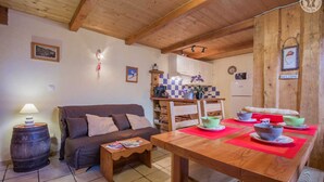 A cozy living room with a wooden dining table set for a meal, a sofa, and a lamp. - LE PIN Cembro LA Norma (LA NORMA VILLARODIN BOURGET)