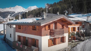 A chalet-style building with a balcony, wooden shutters, and a snow-covered roof. - Chalet LES Violettes (LA PLAGNE TARENTAISE)