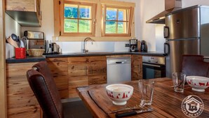 Una cocina con armarios de madera, un refrigerador de acero inoxidable, lavavajillas y una ventana con vistas a zonas verdes.