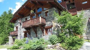 Ein Chalet mit Steinwänden, Holzbalkonen und großen Fenstern.