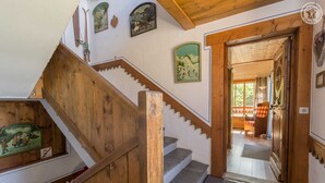 Eine Holztreppe mit Blick auf einen Raum, der einen karierten Stuhl und eine Tür zeigt.