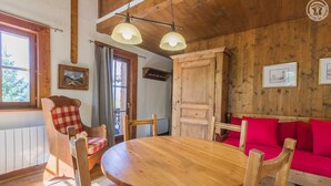 Ein Holzespeisesaal mit Stühlen, ein rotes Sofa und eine Holzkommode in einem Raum mit Holzwänden und -decke.