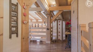 A wooden interior with a high ceiling, wooden beams, and a red mat at the entrance. - Chalet L'escampette - Hauteluce-les-saisies (HAUTELUCE-LES-SAISIES)