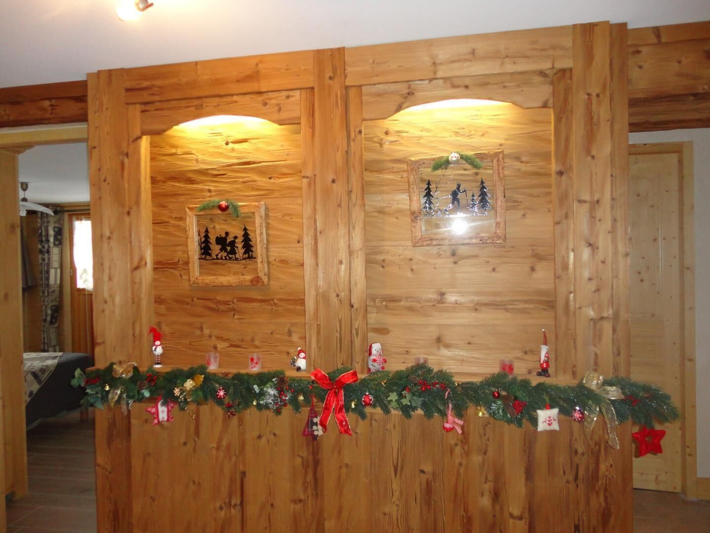 A wooden wall with two framed pictures, a garland with red and gold decorations, and a red star ornament.