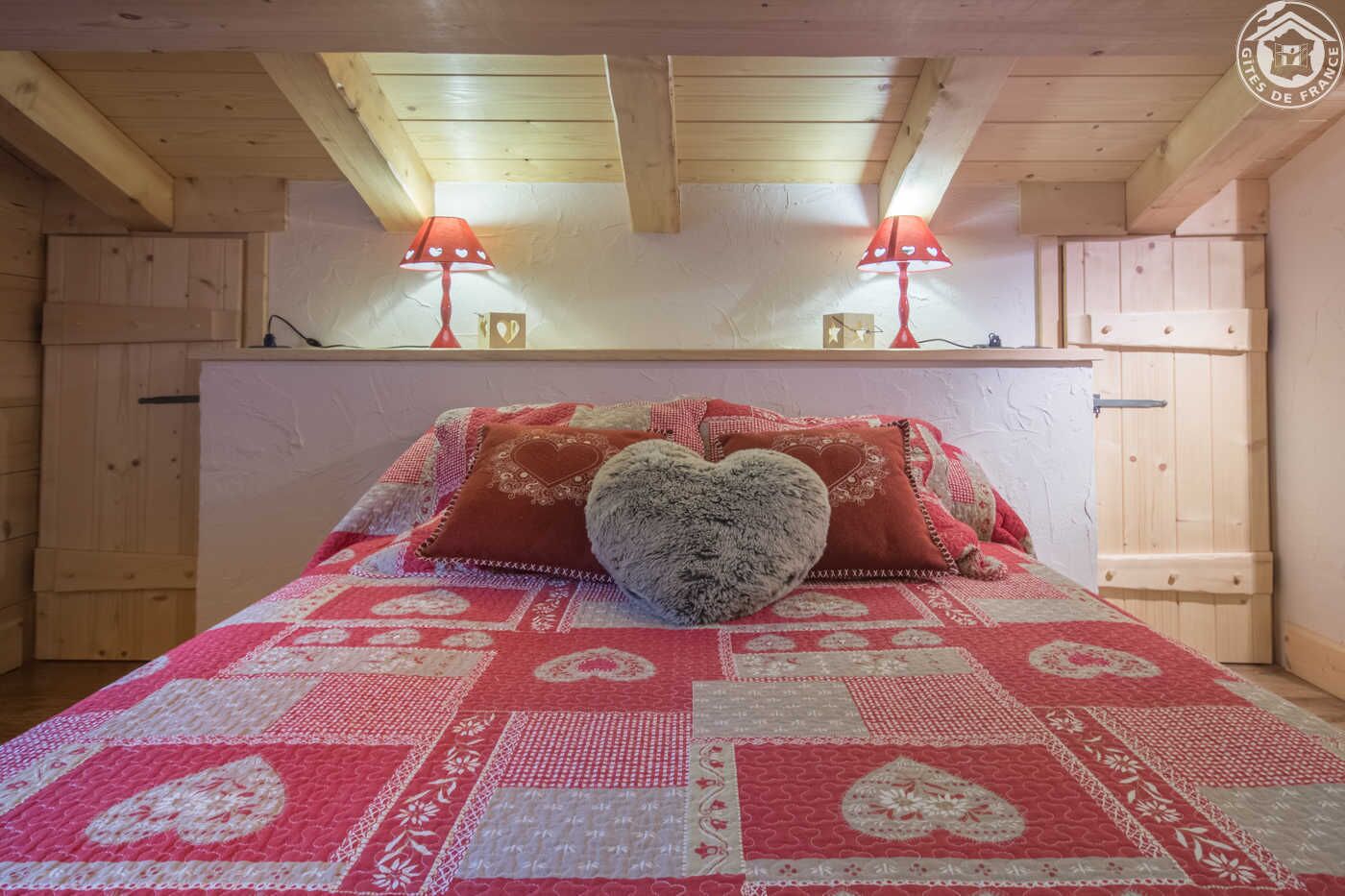 Ett mysigt sovrum med ett vadderat sängöverkast, två sänglampor och en hjärtformad kudde.