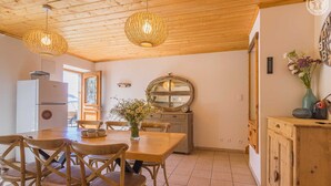Un espace repas avec des meubles en bois, un grand miroir et un plafond en bois.