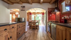 Een houten keuken met een eethoek, houten kastjes en uitzicht op de omgeving.