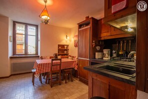 Una cocina acogedora con armarios de madera, una mesa de comedor con mantel a cuadros y una lámpara colgante.