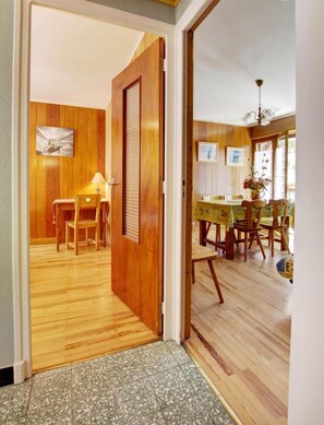 A wooden interior with a dining area, a door leading to another room, and a tiled floor. - LA Bonne EAU N°2 - Valloire (VALLOIRE)