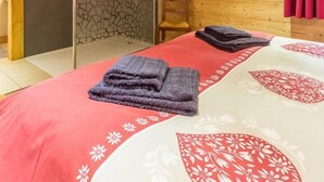 Une pièce de cabane en bois comprenant un lit, un espace douche et un rideau rouge.