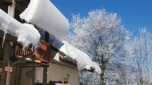 Un edificio con tejados cubiertos de nieve y estalactitas, rodeado de árboles cargados de nieve.