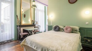 Ein Schlafzimmer mit Bett, Schreibtisch, Stuhl, Spiegel und einer an der Wand hängenden Tennisausrüstung.