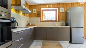 A modern kitchen with stainless steel appliances, wooden paneling, and a window providing natural light. - LA Cachette - Val-cenis (VAL CENIS)