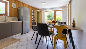 A modern kitchen with a built-in refrigerator, a dining table with chairs, and a view of the outdoors through large windows. - LA Cachette - Val-cenis (VAL CENIS)