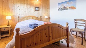Une chambre à coucher aux murs lambrissés, avec un lit, des lampes de chevet, une chaise et un tableau accroché au mur.