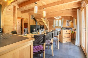 Una cabaña acogedora de madera con comedor, cocina y una escalera que sube a un nivel superior.
