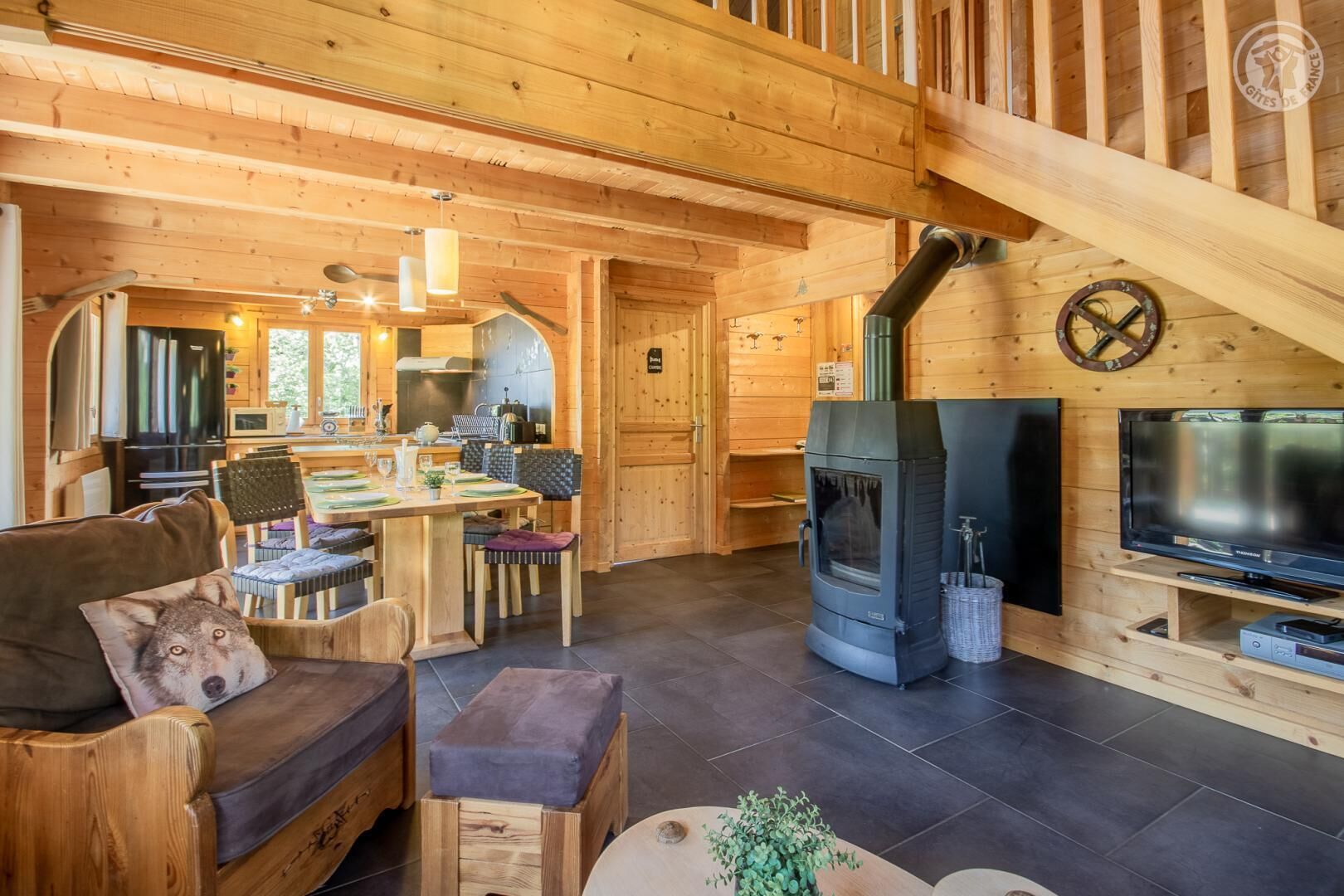 Un intérieur chaleureux en bois, avec un coin repas, un canapé, un téléviseur et un poêle à bois.