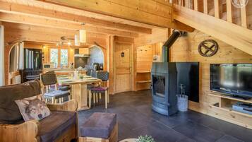 Un intérieur chaleureux en bois, avec un coin repas, un canapé, un téléviseur et un poêle à bois.