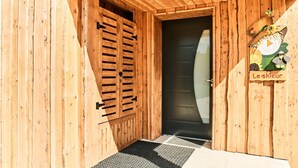 Un edificio in legno con una porta nera e un cartello con su scritto "Le skieur".