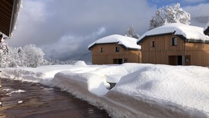 Un edificio in legno con tetti imbiancati dalla neve, circondato da alberi innevati e un pontile in legno.