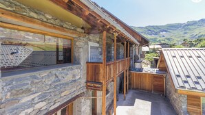 Un bâtiment en pierre doté de balcons en bois et offrant une vue sur les montagnes.